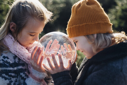 Bruder und Schwester schauen in eine mit Schnee gefüllte Kristallkugel und wünschen sich etwas - MJF02214