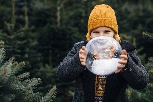 Kleiner Junge hält eine mit Schnee gefüllte Kristallkugel und wünscht sich etwas - MJF02228