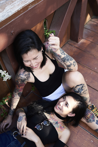 Tattooed lesbian couple laughing and having fun on wooden bridge stock photo