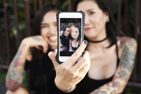 Frau hält Handy mit Selfie von sich mit ihrer lesbischen Partnerin - IGGF00263