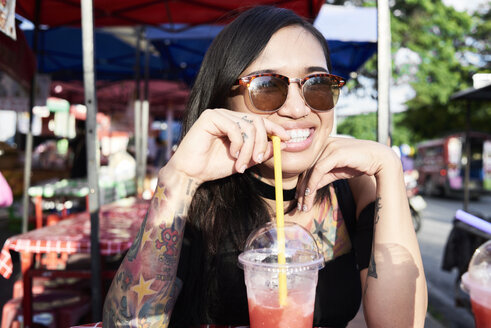 Portrait of happy woman drinking a smoothie outdoors - IGGF00266