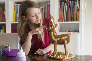 Smiling girl with homemade gingerbread reindeer at home - SARF03448