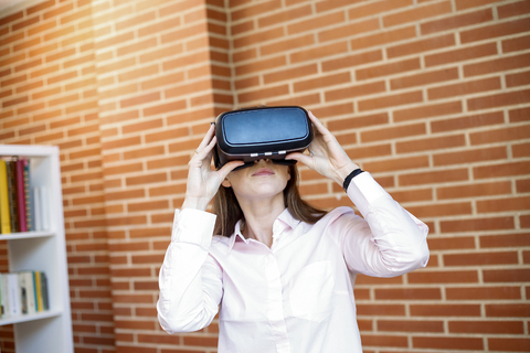 Businesswoman wearing VR glasses in office stock photo