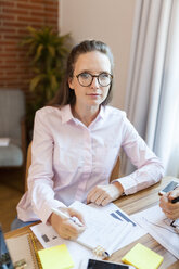 Portrait of businesswoman taking notes on table in office - VABF01431