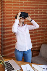 Businesswoman wearing VR glasses in office - VABF01447