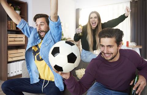 Begeisterte Fußballfans, die fernsehen und jubeln, lizenzfreies Stockfoto