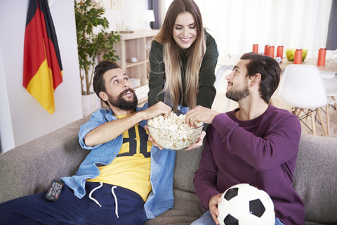 Frau serviert Freunden während eines Fußballspiels einen Snack, lizenzfreies Stockfoto