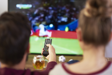Pärchen schaut Fußballspiel im Fernsehen, lizenzfreies Stockfoto