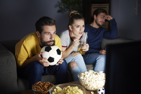 Worried friends sitting on the sofa watching Tv stock photo