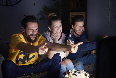 Excited friends sitting on the sofa watching Tv - ABIF00097