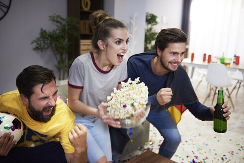 Aufgeregte Freunde mit Bier und Popcorn beim Fernsehen - ABIF00099