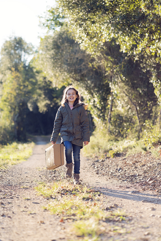Happy girl walking with suitcase in nature stock photo