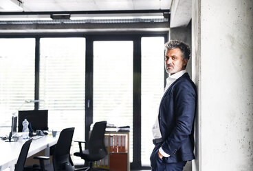 Portrait of confident mature businessman standing in office - HAPF02515
