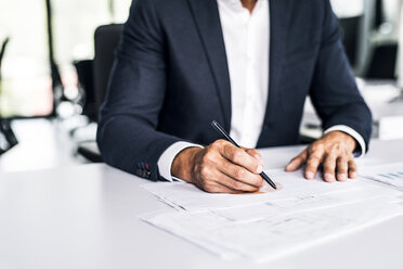 Close-up of businessman with documents at desk in office - HAPF02526