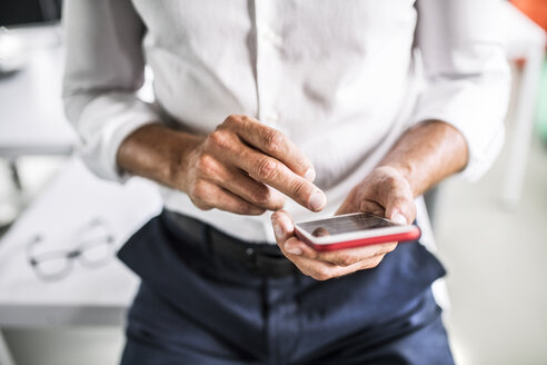 Nahaufnahme eines Geschäftsmannes, der ein Mobiltelefon im Büro benutzt - HAPF02537