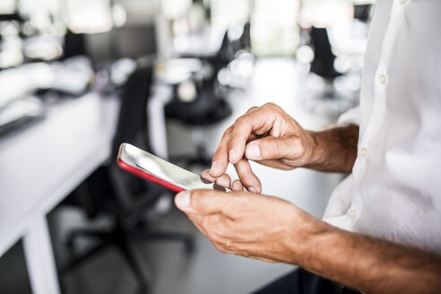 Nahaufnahme eines Geschäftsmannes, der ein Mobiltelefon im Büro benutzt - HAPF02538