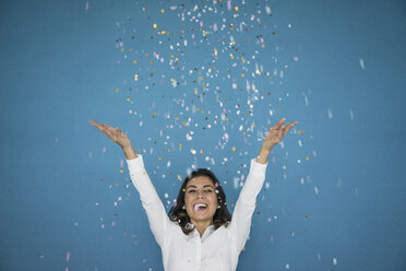 Portrait of laughing woman throwing confetti in the air - MOEF00432