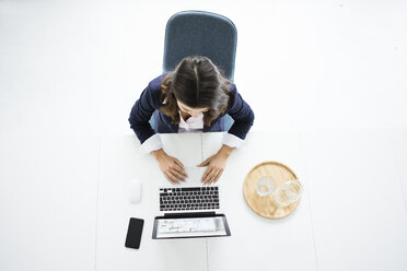 Businesswoman sitting at desk in the office working on laptop, top view - MOEF00440