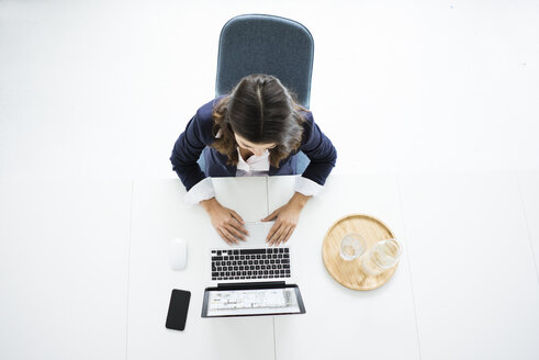 Geschäftsfrau sitzt am Schreibtisch im Büro und arbeitet am Laptop, Draufsicht - MOEF00440