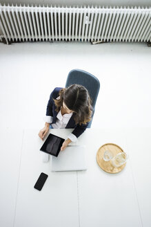 Geschäftsfrau sitzt am Schreibtisch im Büro und arbeitet an einem Tablet, Ansicht von oben - MOEF00442