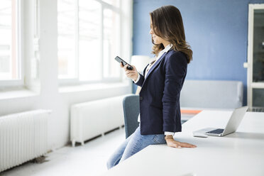 Geschäftsfrau benutzt Mobiltelefon im Büro - MOEF00459