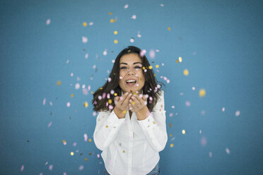 Portrait of laughing woman throwing confetti in the air - MOEF00473