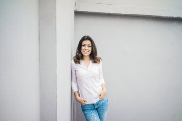 Portrait of laughing young woman leaning against wall - MOEF00481