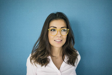 Porträt einer lächelnden Frau mit Brille vor einem blauen Hintergrund - MOEF00490