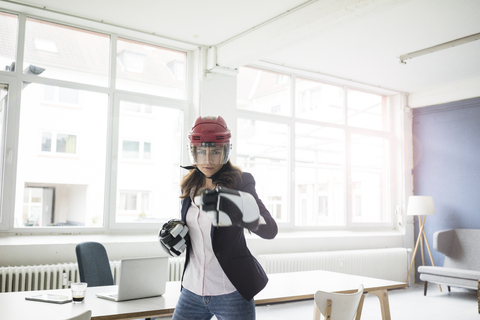 Porträt einer Geschäftsfrau mit Eishockeyausrüstung im Büro, lizenzfreies Stockfoto