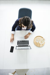 Geschäftsfrau sitzt am Schreibtisch im Büro und arbeitet am Laptop, Draufsicht - MOEF00497