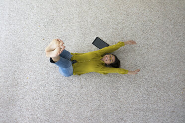 Laughing woman lying on carpet doing stretching exercises, top view - MOEF00502