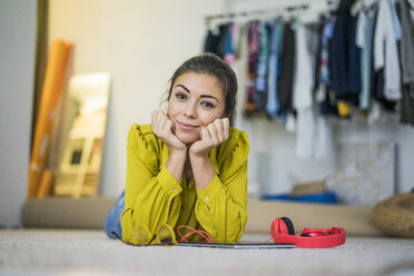 Portrait of smiling young woman lying on the floor with headphones and tablet - MOEF00510