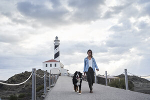 Spanien, Menorca, Berner Sennenhund beim Spaziergang mit seinem Besitzer im Freien am Leuchtturm - IGGF00289