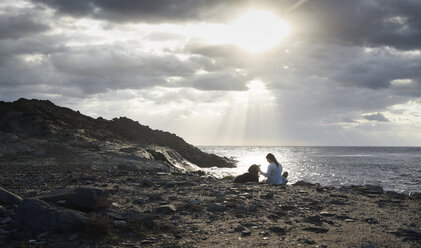 Bernese mountain dog sitting next to his owner outdoors with sunlight at sunrise - IGGF00290