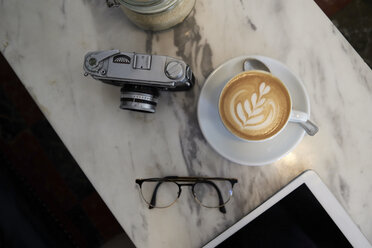 From above view of a coffee cup analogue camera and glasses on a marble table - IGGF00293