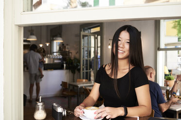 Glückliche asiatische Frau in einem Café neben dem Fenster - IGGF00295