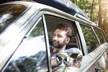 Smiling young man in car in forest - FKF02790