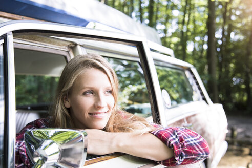 Lächelnde junge Frau im Auto im Wald - FKF02800
