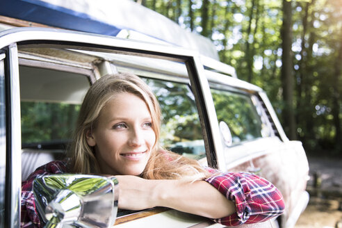 Smiling young woman in car in forest - FKF02800