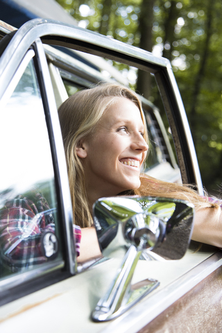 Glückliche junge Frau im Auto im Wald, lizenzfreies Stockfoto