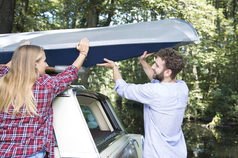 Smiling young couple taking canoe from car roof stock photo