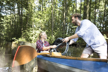 Happy young couple entering canoe in a forest brook - FKF02808