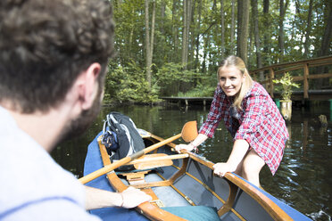 Happy young couple entering canoe in a forest brook - FKF02809