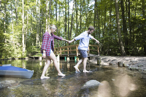 Young couple crossing a forest brook - FKF02811