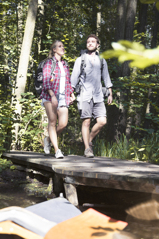 Young couple crossing a bridge in forest stock photo