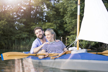 Happy young couple enjoying a trip in a canoe with sail - FKF02818