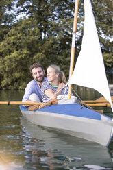 Happy young couple enjoying a trip in a canoe with sail - FKF02819
