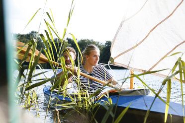 Young couple enjoying a trip in a canoe with sail on a lake - FKF02823