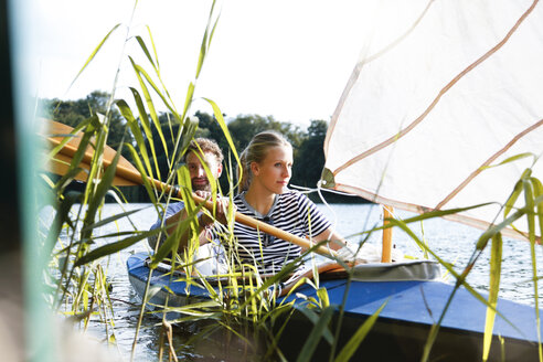 Junges Paar genießt einen Ausflug in einem Kanu mit Segel auf einem See - FKF02823