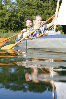 Young couple enjoying a trip in a canoe with sail on a lake - FKF02829